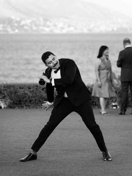 Groomsman playfully posing during cocktail hour at luxury Athens Riviera wedding reception.
