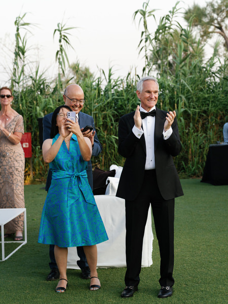 Guests clapping during wedding reception at Island Resort Athens Riviera outdoor venue.