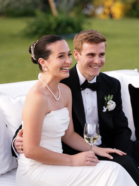 Bride and groom seated together smiling during wedding speeches at The Residence Island Resort Athens Riviera.