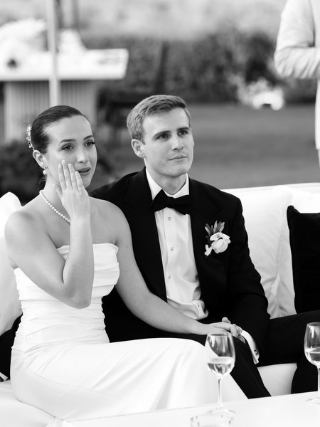 Bride wiping away tears while listening to heartfelt speech at Athens Riviera wedding reception.