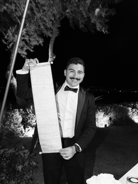 Groomsman holding speech notes during nighttime reception at Athens Riviera wedding.
