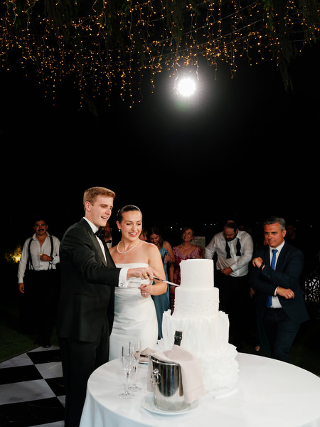 Bride and groom cutting multi-tier wedding cake at The Residence Island Resort Athens Riviera at night.
