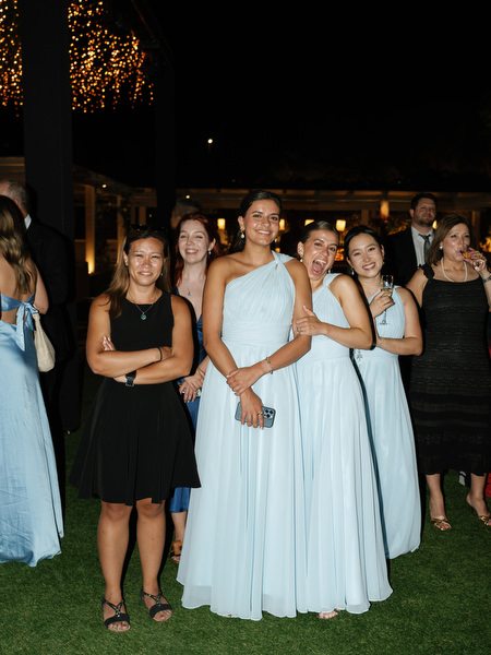Bridesmaids in pastel blue dresses reacting during nighttime wedding celebration at The Residence Athens.