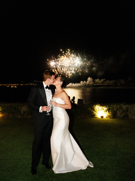 Bride and groom kissing with fireworks over the Athenian Riviera at Island Resort Athens wedding.