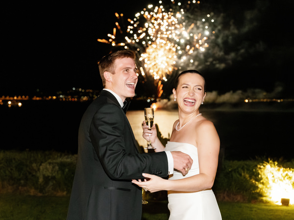 Bride and groom holding sparkler with fireworks in the background at Island Resort Athens Riviera.