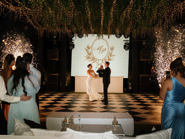 Bride and groom dancing in front of illuminated wedding monogram at Island Resort Athens Riviera.