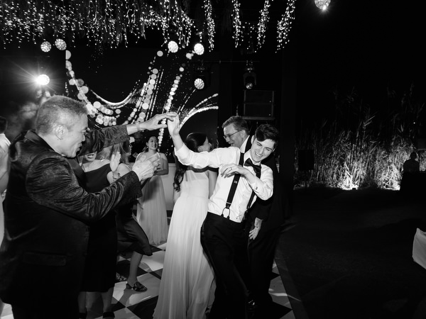 Guests spraying champagne during high-energy wedding celebration at The Residence Athens Riviera.