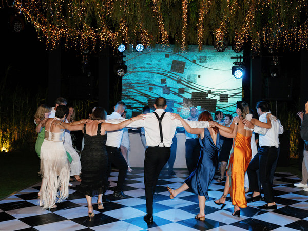 Wedding guests holding hands in circle dance at Athens Riviera luxury wedding reception.