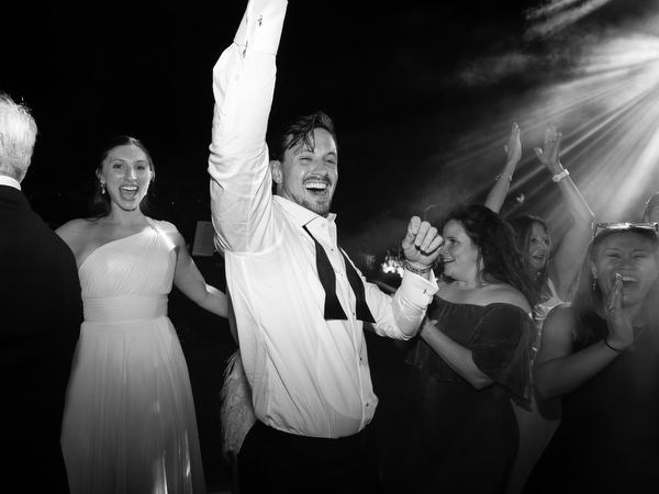 Groomsman celebrating with raised arm during Island Resort Athens Riviera wedding party.