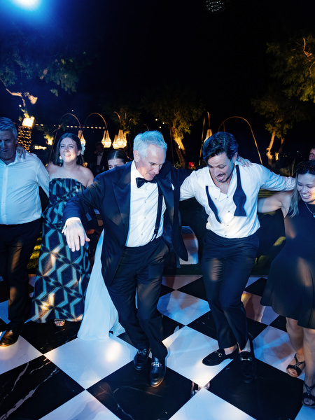 Groomsman dancing with loosened tie during high-energy Island Resort Athens Riviera wedding party.
