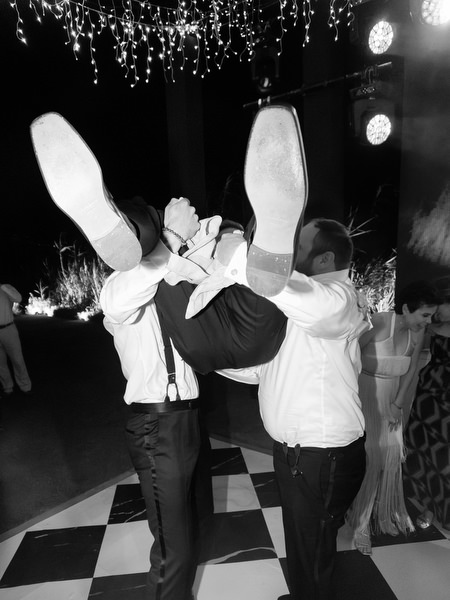 Guests lifting groom under hanging fairy lights at The Residence Island Resort Athens Riviera reception.