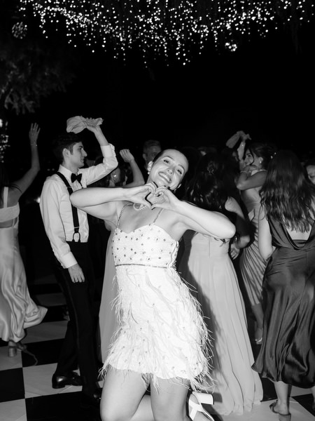 Bride in feather party dress dancing joyfully on black and white dance floor at The Residence Island Resort Athens Riviera.