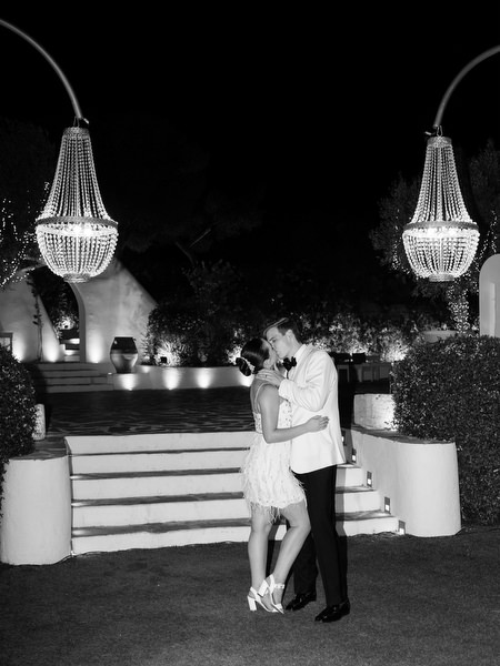 Bride and groom sharing romantic kiss under crystal chandeliers at The Residence Island Resort Athens Riviera at night.
