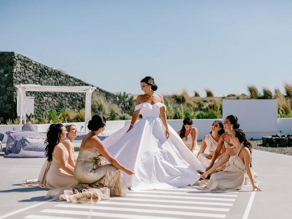 Bridesmaids adjusting bride’s gown at Eros Santorini.