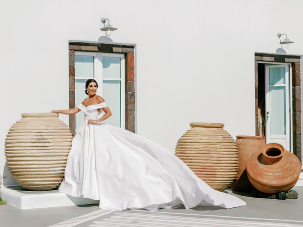 High-fashion bridal portrait at Eros Santorini overlooking caldera.