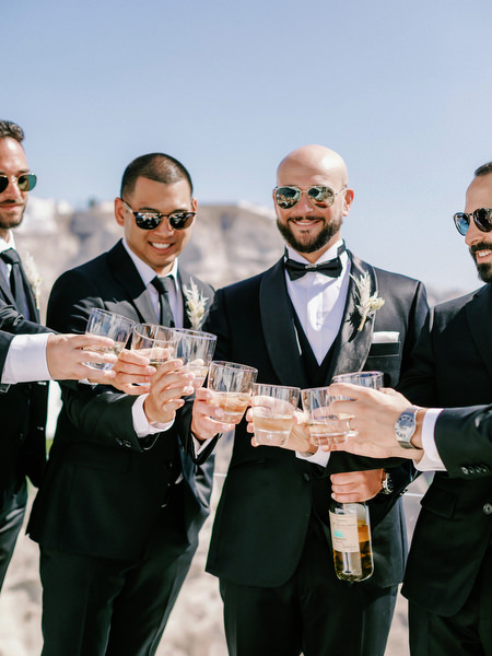Groom and friends champagne toast Santorini wedding.