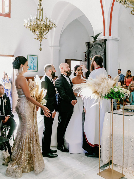 Wedding ceremony inside Santorini church with chandeliers.