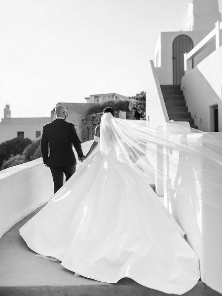 Bride and groom walking Santorini terrace black and white.