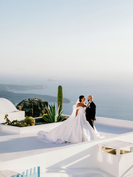 Bride and groom overlooking Santorini caldera at sunset.