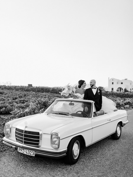 Bride and groom in vintage convertible Santorini.