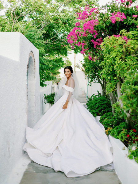 Bride in dramatic gown framed by bougainvillea.