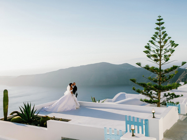 Bride and groom portrait overlooking volcanic cliffs Santorini.