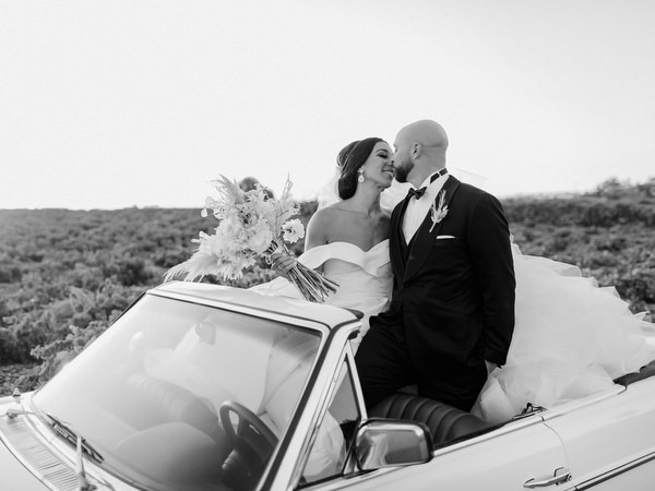 Bride and groom portrait on a vintage convertible car at Santorini.