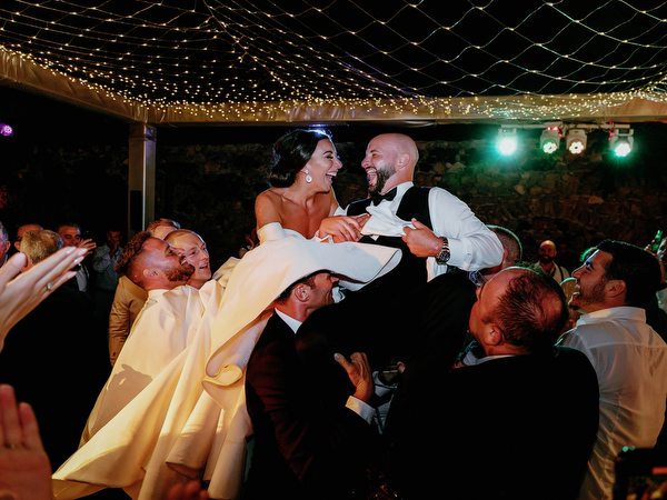 Guests lifting bride and groom during Jewish celebration.