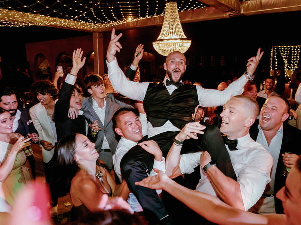 Groom lifted on chair at Arts Factory Santorini wedding.