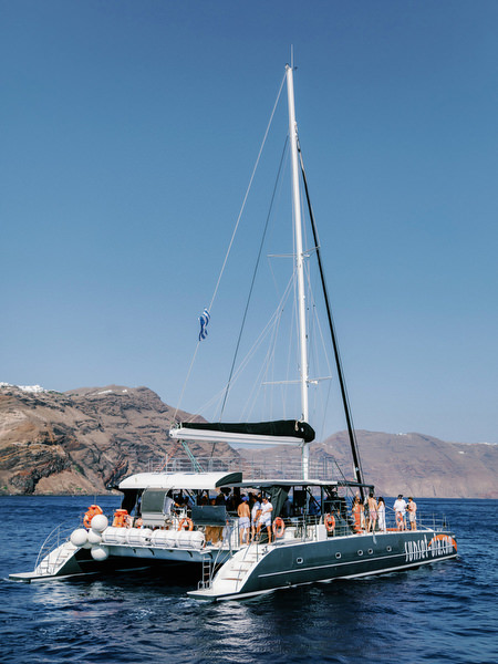 Luxury catamaran sailing across Santorini caldera