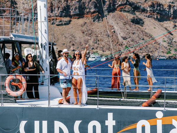 Wedding guests cheering on catamaran during Santorini cruise