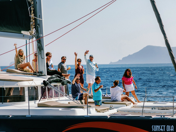 Guests enjoying views of Santorini cliffs during catamaran cruise