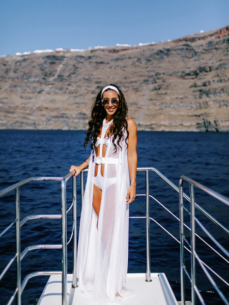 Bride posing on catamaran bow during Santorini sailing celebration