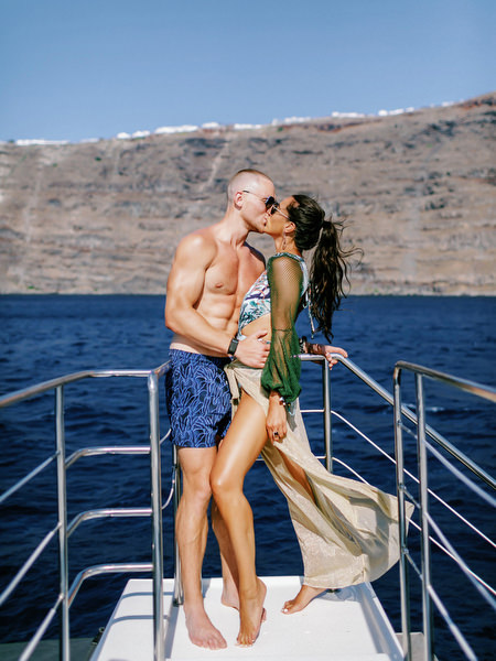 Couple kissing on deck during Santorini wedding catamaran cruise