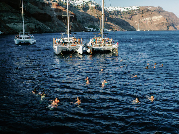 Guests swimming in volcanic waters during Santorini boat celebration