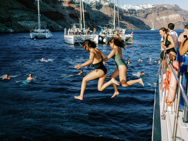 Guest diving into water during Santorini wedding boat cruise