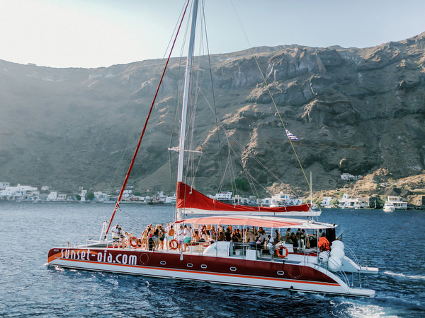 Catamaran sailing near Santorini cliffs during wedding weekend cruise