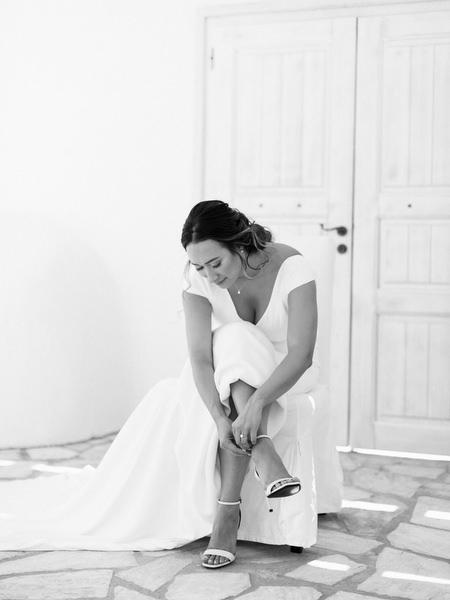 Bride putting on heels in Santorini villa before Venetsanos Winery wedding.