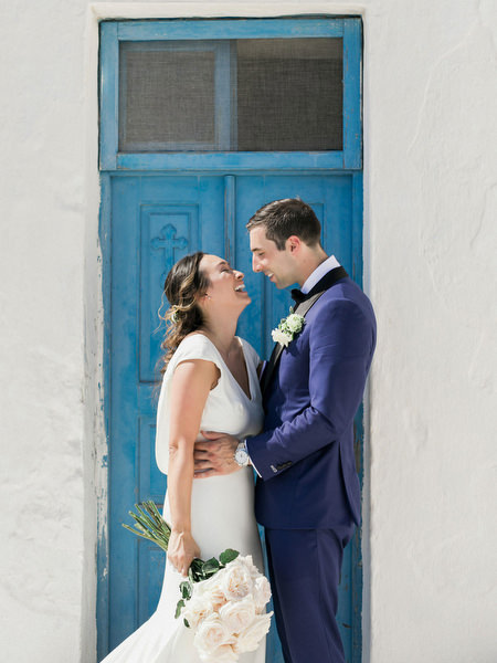 Bride and groom portrait with blue door in Santorini before winery wedding.