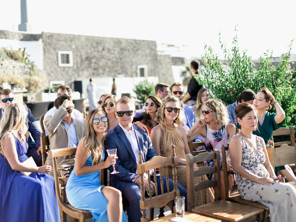Wedding guests seated at Venetsanos Winery ceremony overlooking Santorini caldera.