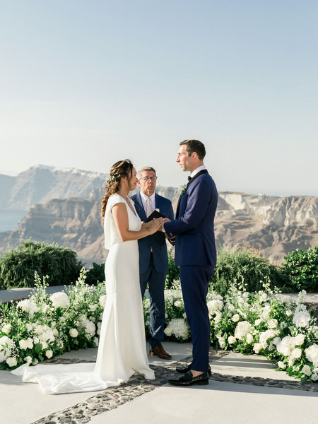 Newlyweds at Venetsanos Winery ceremony overlooking Santorini caldera.