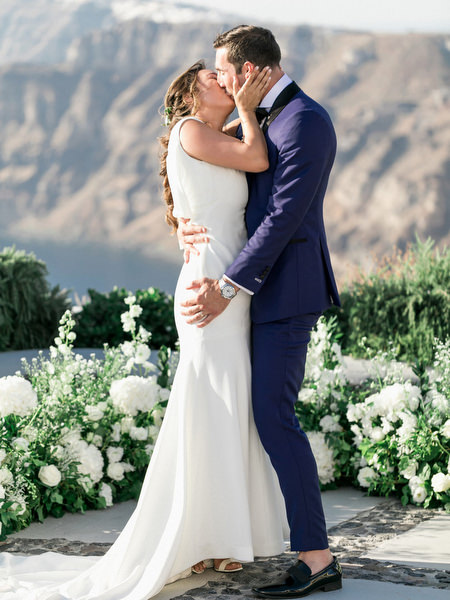 Bride and groom kissing at Venetsanos Winery Santorini wedding ceremony.