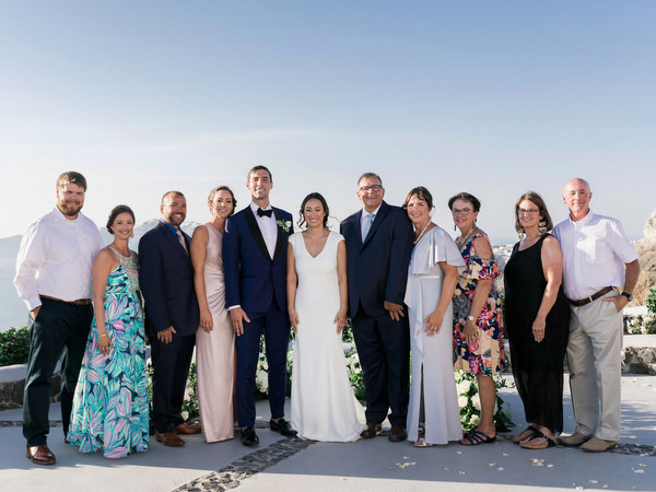 Family portrait at Venetsanos Winery wedding overlooking Santorini cliffs.