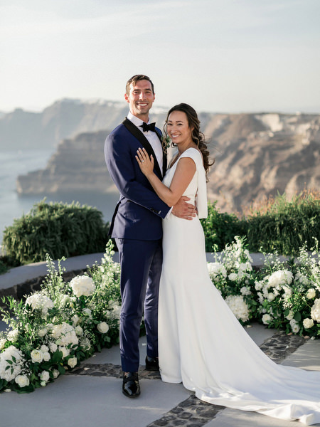Newlyweds portrait overlooking Santorini caldera at Venetsanos Winery.