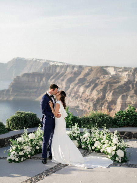 Romantic Santorini cliffside wedding portrait at Venetsanos Winery.