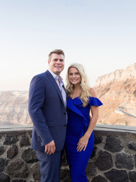 Guests at Venetsanos Winery terrace overlooking Santorini cliffs.