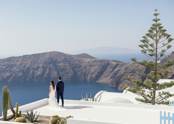 Bride and groom with Santorini caldera backdrop.