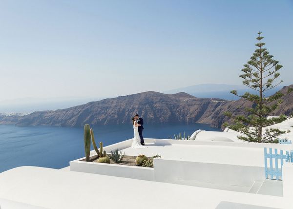 Bride and groom with Santorini caldera backdrop.