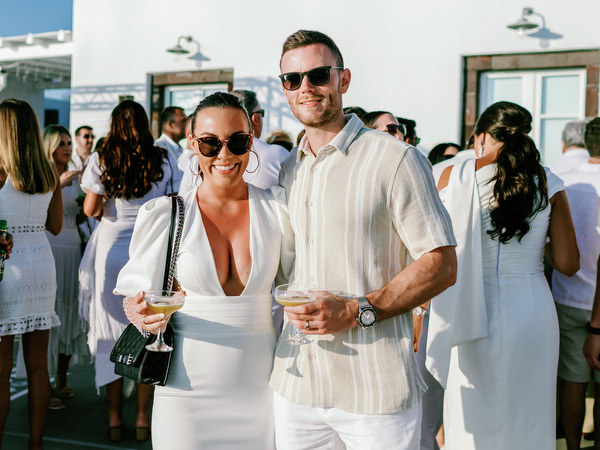 Couple portrait of guests in white outfits at Santorini welcome party