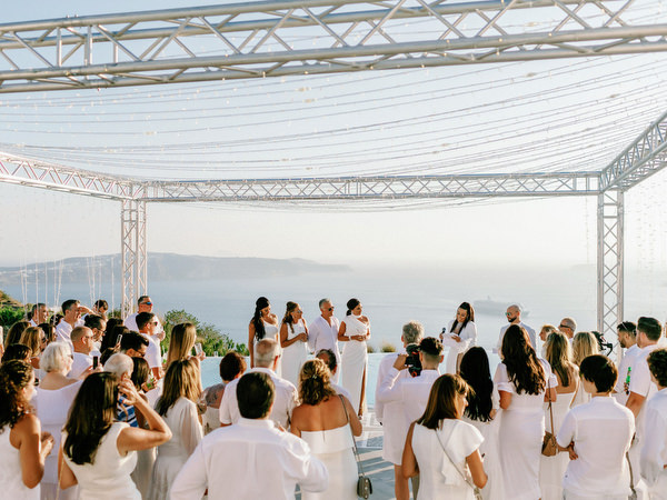 Bride and groom cheering with guests at Santorini welcome party